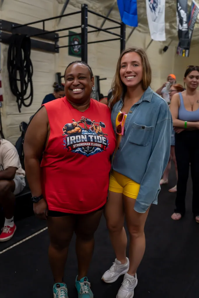 Two athletes side by side at a strongman competition, both grinning