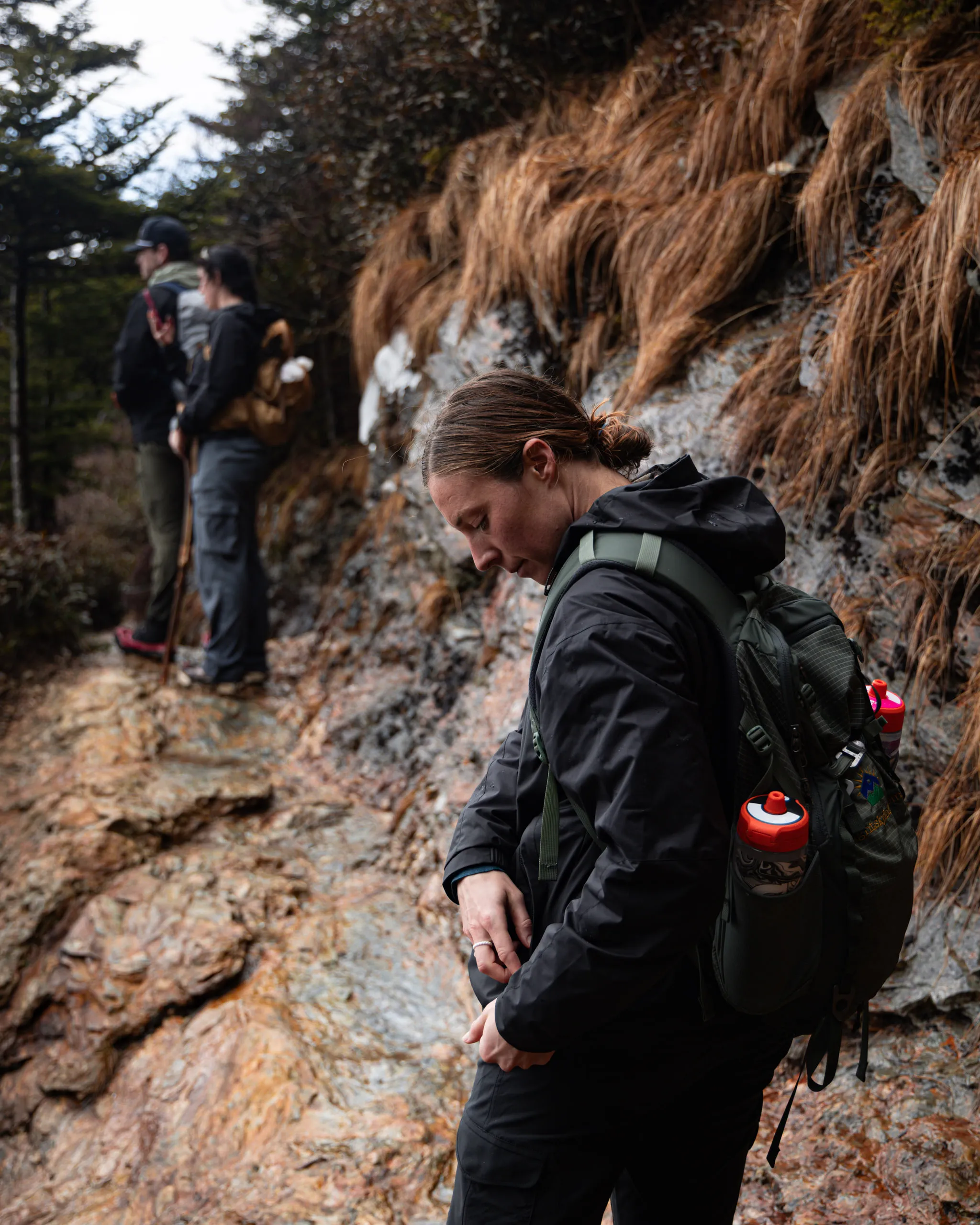 A small group stopped partway up a rocky mountain trail